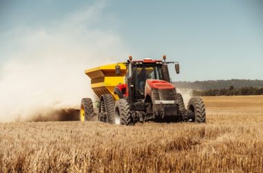 pexels-photo-14242145-14242145 A powerful red and yellow tractor working in a sunny wheat field, symbolizing modern farming techniques.